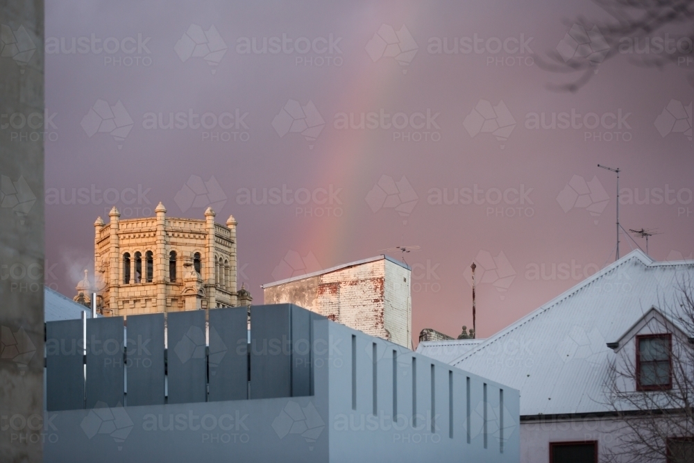 rainbow above buildings in a city - Australian Stock Image
