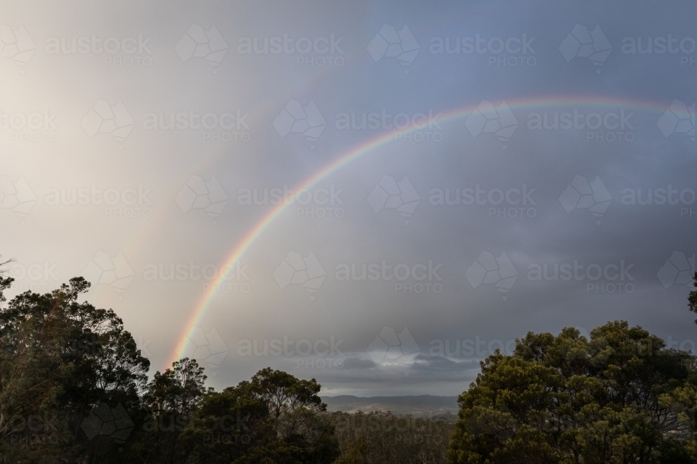 Rainbow above trees and nature scene - Australian Stock Image