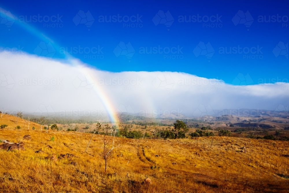 Rainbow and cloud over a rural property in the Scenic Rim - Australian Stock Image