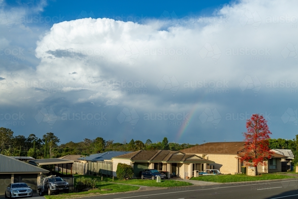 Rainbow and storm clouds over suburban houses. - Australian Stock Image