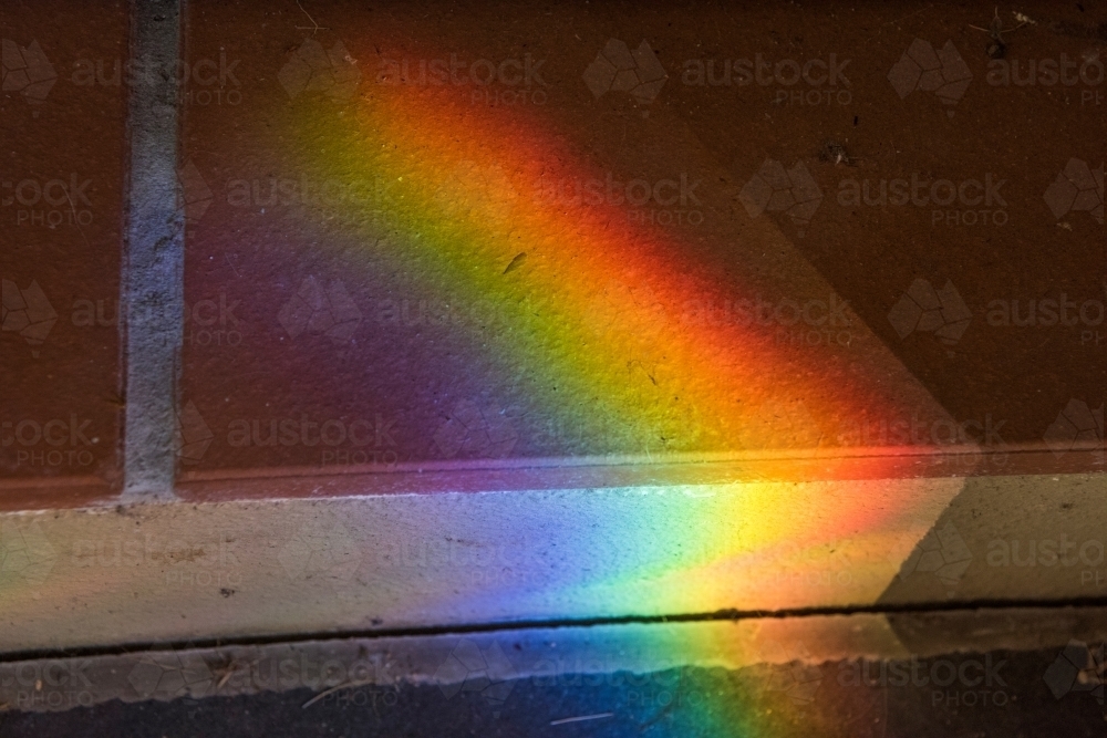 Rainbow coloured light prism shining on tiles - Australian Stock Image