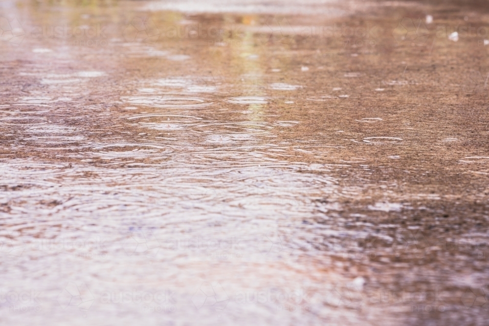 raindrops falling on a concrete surface - Australian Stock Image