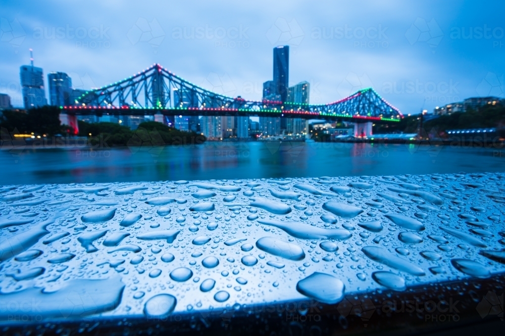Raindrops on a metal railing with the Story Bridge in the background - Australian Stock Image