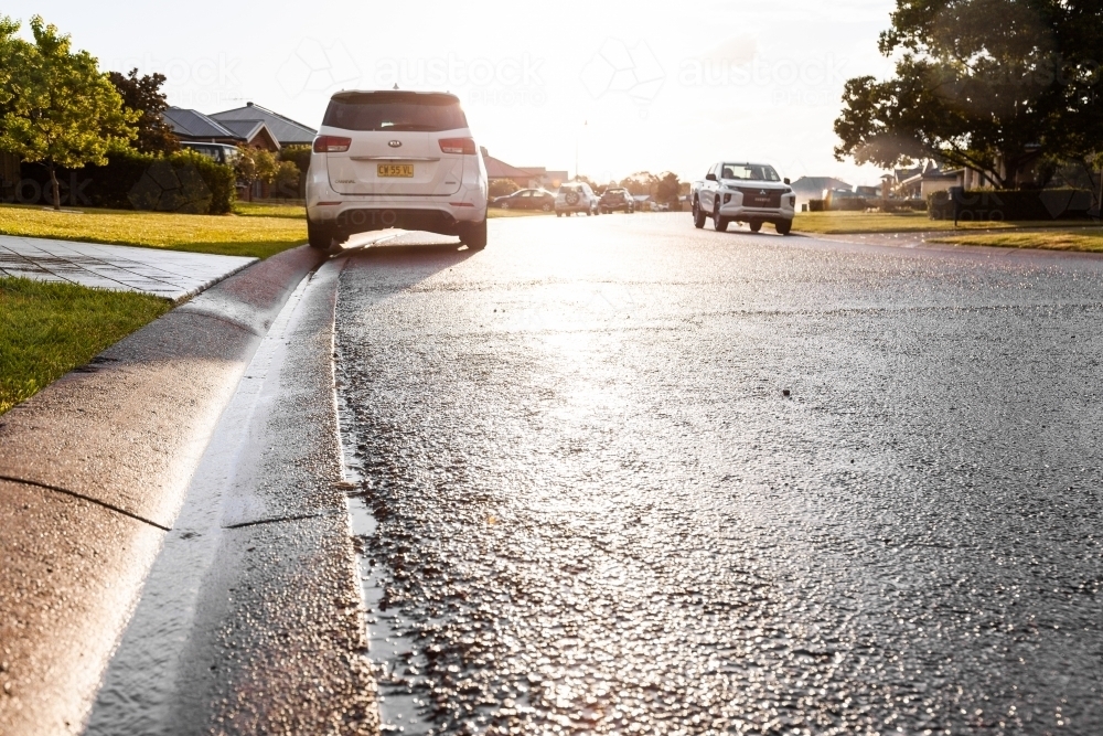 Rainwater running down gutter to stormwater drain in street - Australian Stock Image