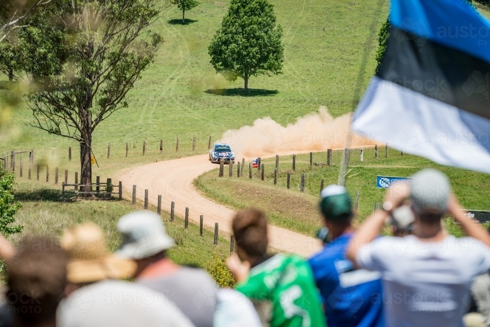 Rally car taking a corner from afar with crowd in the foreground - Australian Stock Image