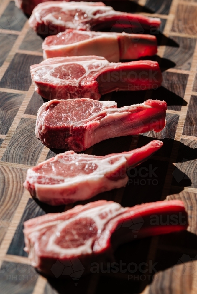 Raw lamb cutlets arranged on a wooden chopping board - Australian Stock Image