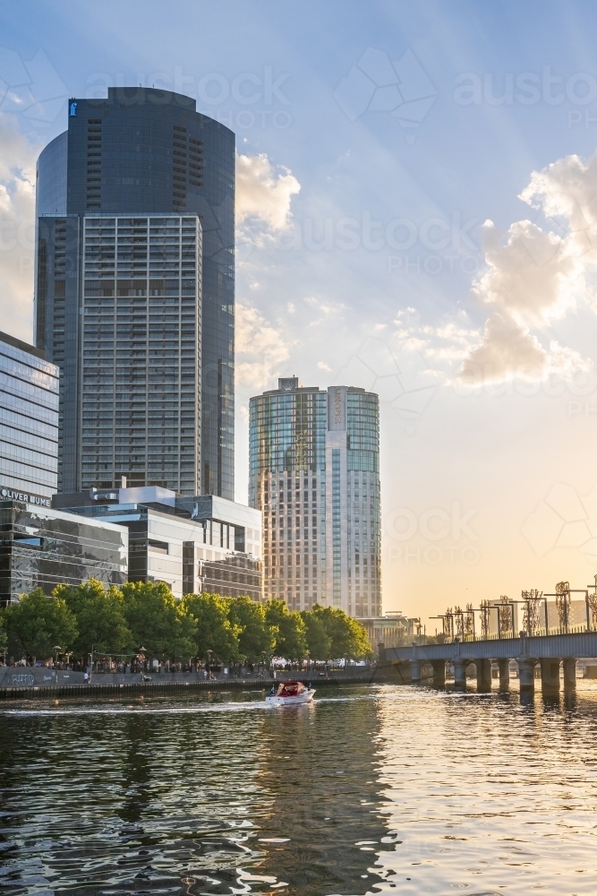 Rays of sunshine over an inner city river with high rise buildings along its banks - Australian Stock Image