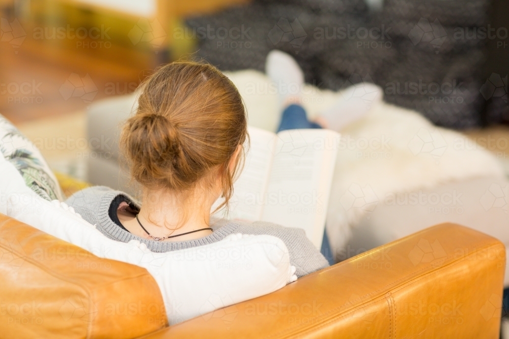 Reading a book with her feet up - Australian Stock Image