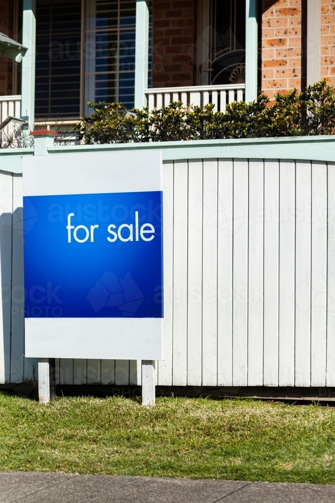 Real estate for sale sign outside white front fence of home in Newcastle - Australian Stock Image