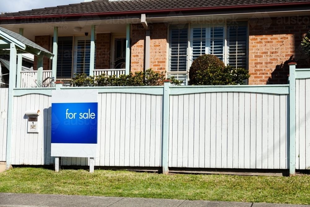 Real estate for sale sign outside white front fence of home in Newcatle - Australian Stock Image