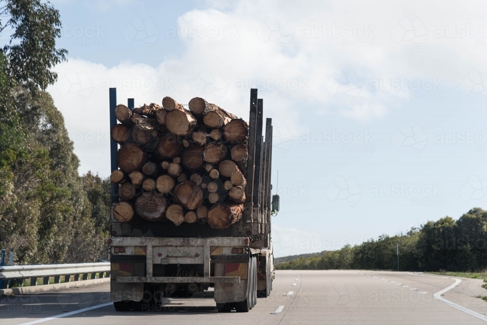 rear view of a truck full of tree logs on a rural highway - Australian Stock Image