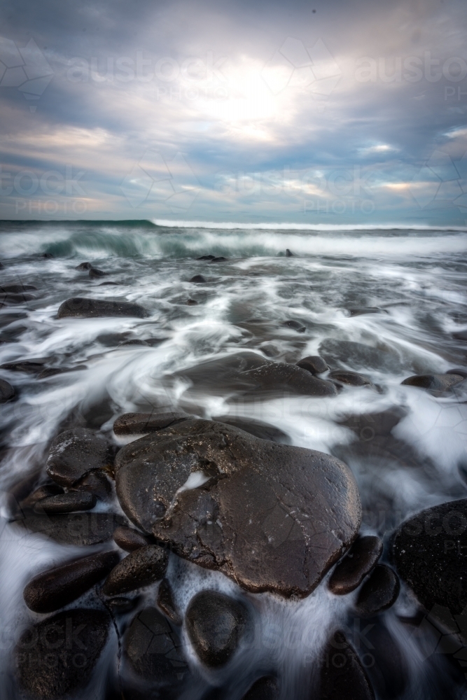 Receding Tide During a Moody Morning on a Black Rock Beach - Australian Stock Image