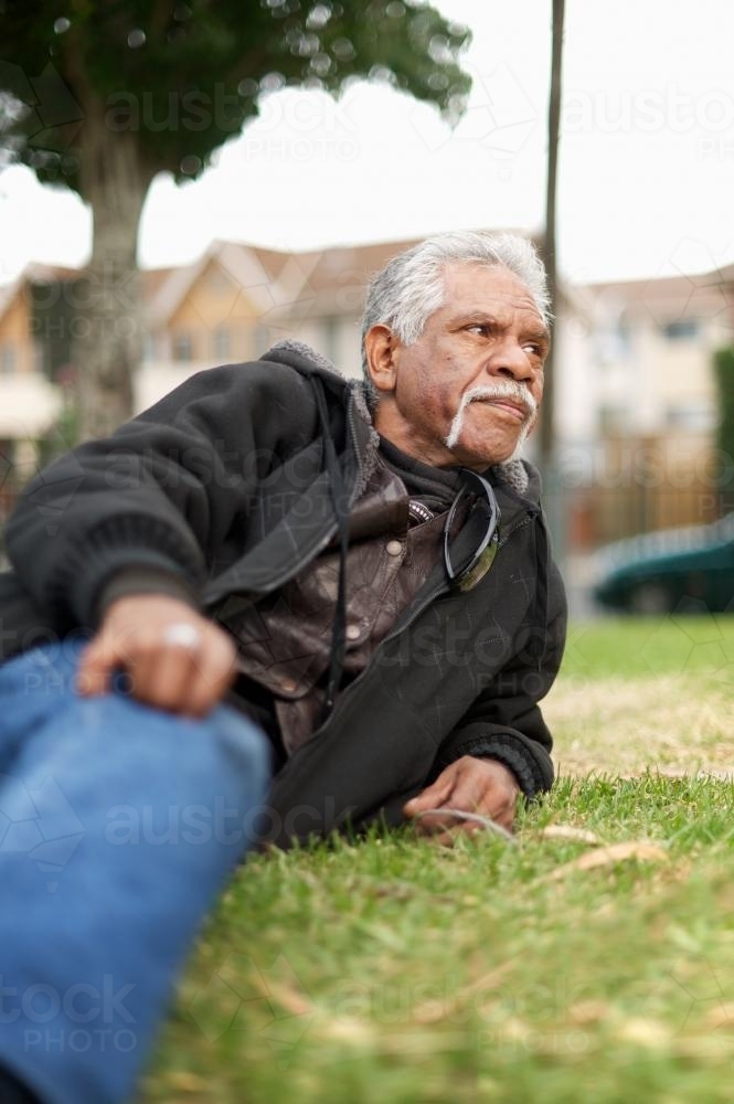 Reclining Aboriginal Man on Grass Outside - Australian Stock Image