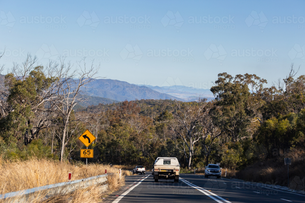 recommended speed sign for bend in highway road descending from great dividing range hills - Australian Stock Image