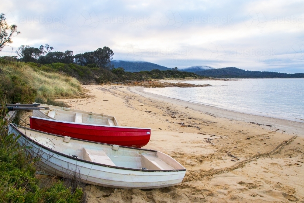 Red and white boats pulled up on beach - Australian Stock Image