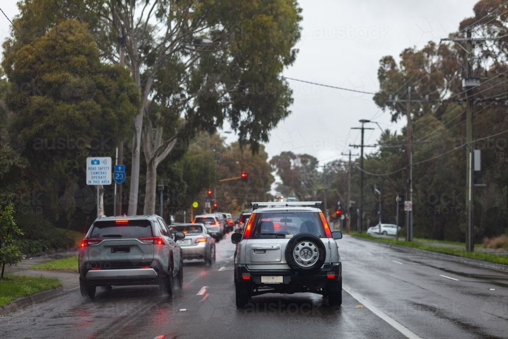 Image of Red break lights of cars on slippery wet road stopping at