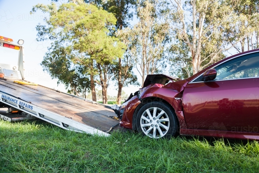Red car after a front end collision road accident being towed onto a tow truck - Australian Stock Image