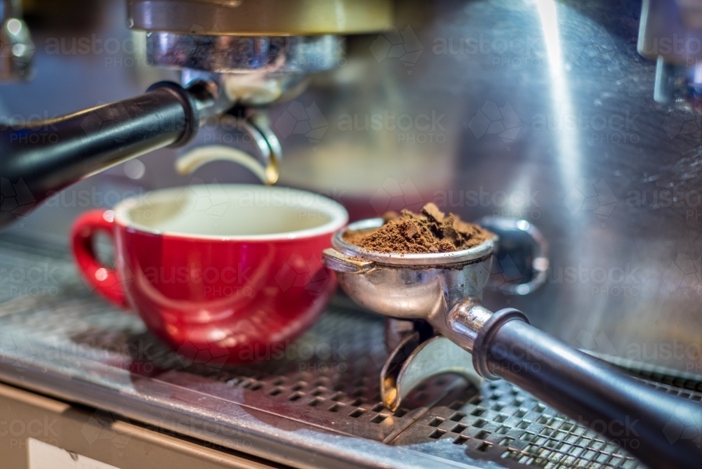 Red coffee cup on coffee machine with ground coffee - Australian Stock Image