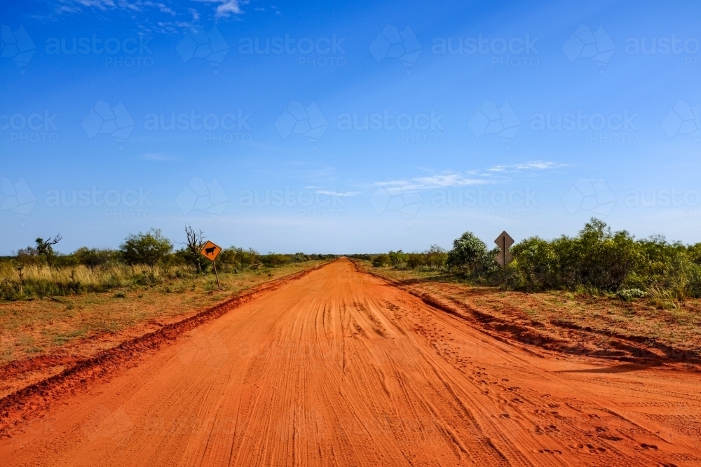 Red dirt outback road leading to blue sky - Australian Stock Image