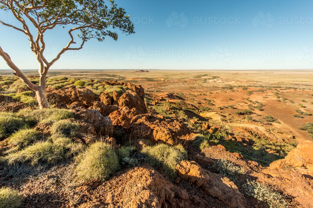 Image of Red dirt ridges overlooking a vast outback plain. - Austockphoto