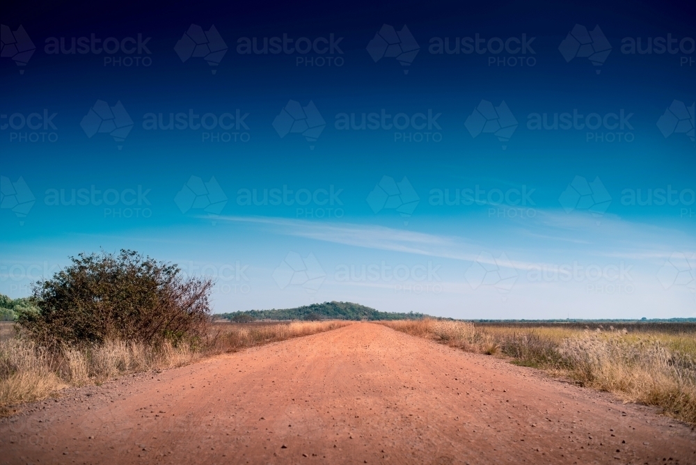 Red dirt road and big blue skies in Darwin, Northern Territory - Australian Stock Image