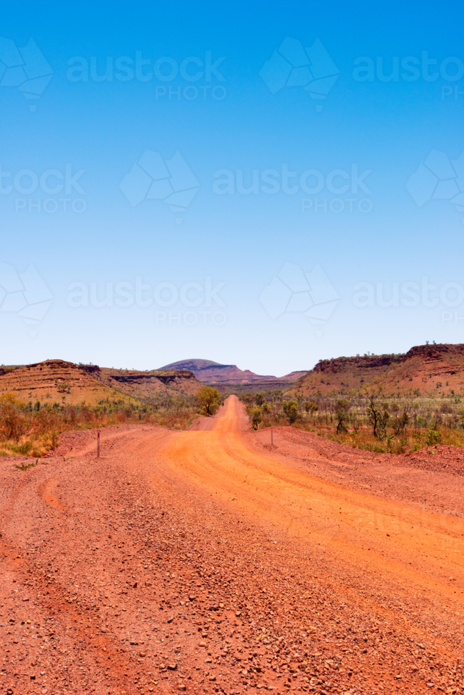 Red dirt road leading to horizon in karijini national park - Australian Stock Image