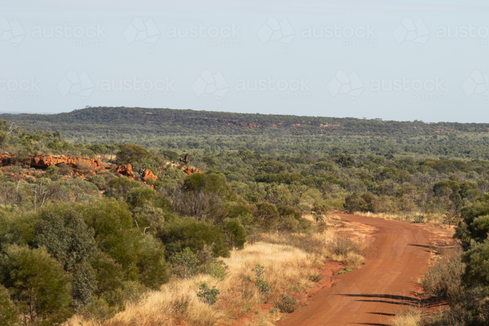 Red dirt road winding around a hill - Australian Stock Image