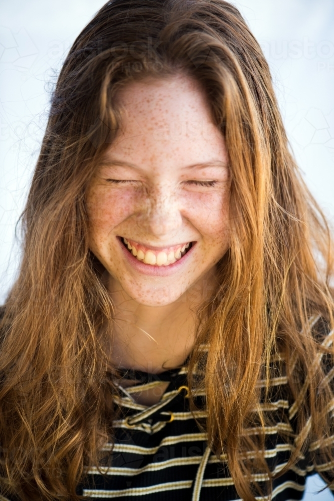 Red haired teenager screwing up face laughing - Australian Stock Image