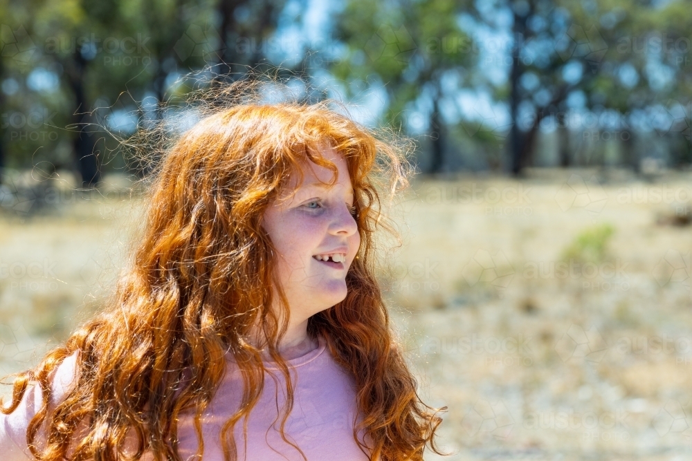 red-headed fair-skinned child outdoors with messy long orange hair - Australian Stock Image