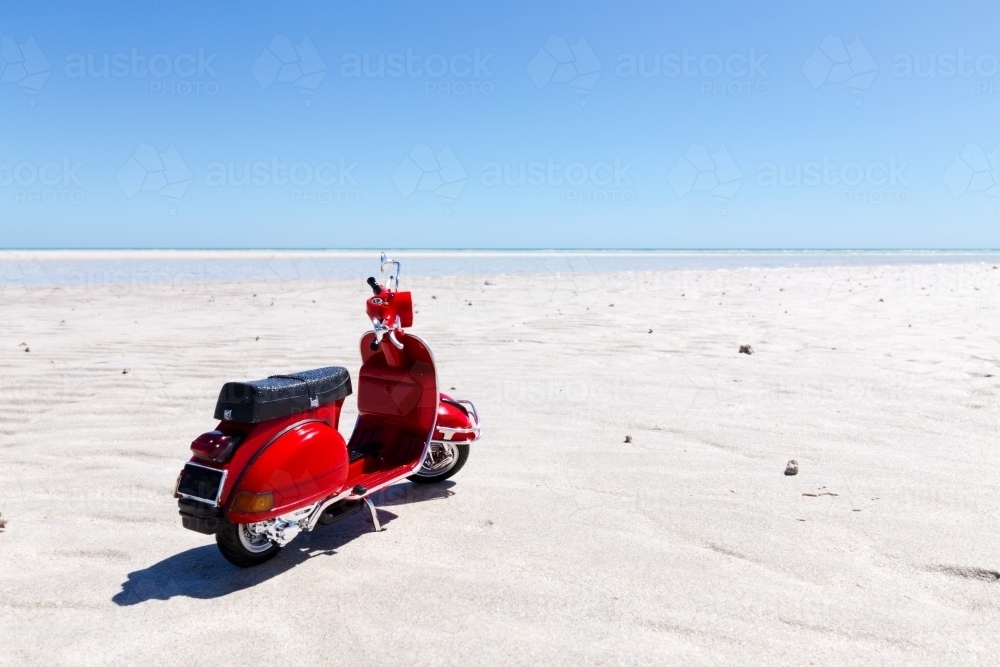 red motorbike on white sandy beach - Australian Stock Image