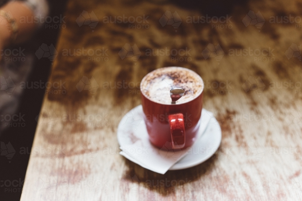 Red mug of coffee on a wooden table - Australian Stock Image