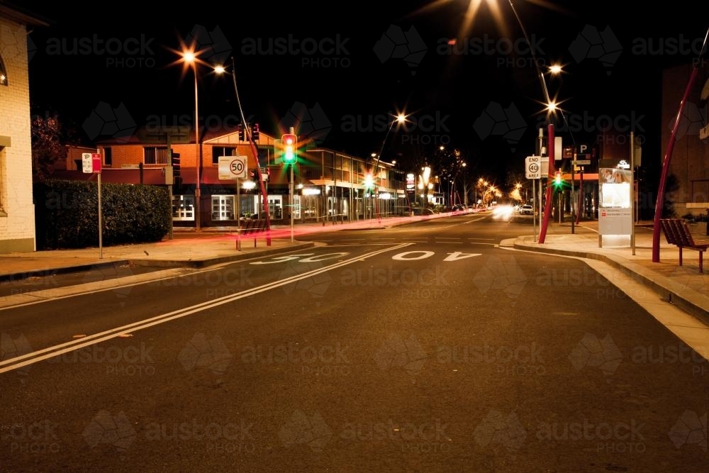 Red orange and green traffic lights in a small town at night - Australian Stock Image