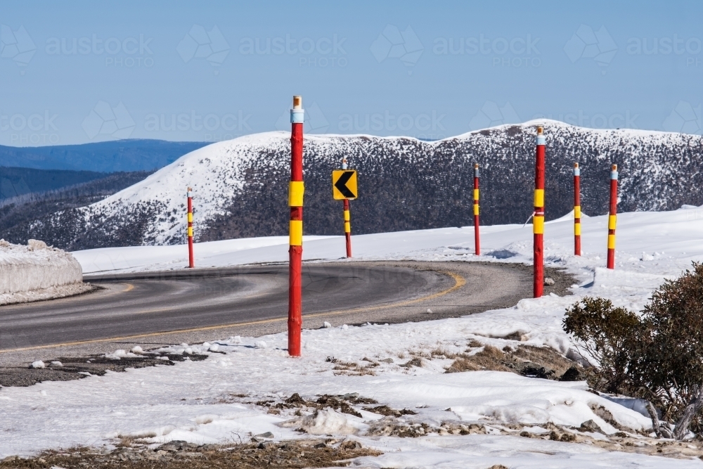 Red poles marking the road in rural snowy landscape - Australian Stock Image