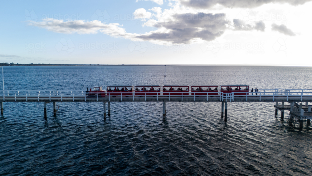 Red tourist train making its way along the pier - Australian Stock Image