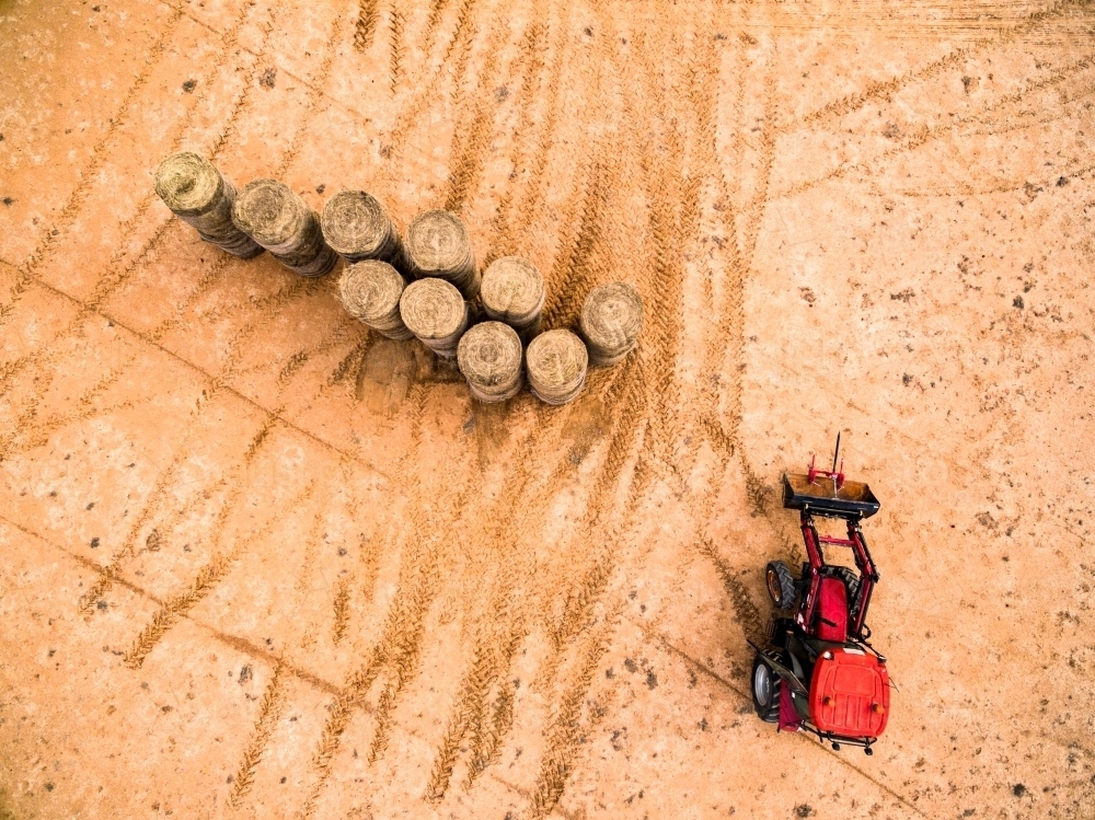 Red tractor moving  large hay bales. - Australian Stock Image