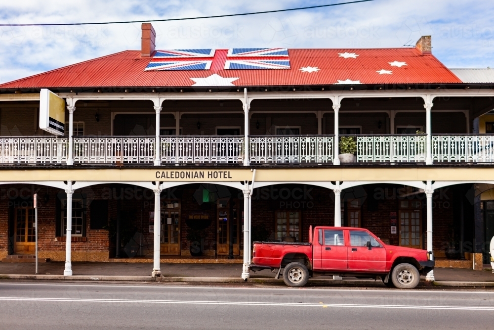 Red ute parked outside of Aussie pub with anti-lockdown australian red ensign flag on roof - Australian Stock Image