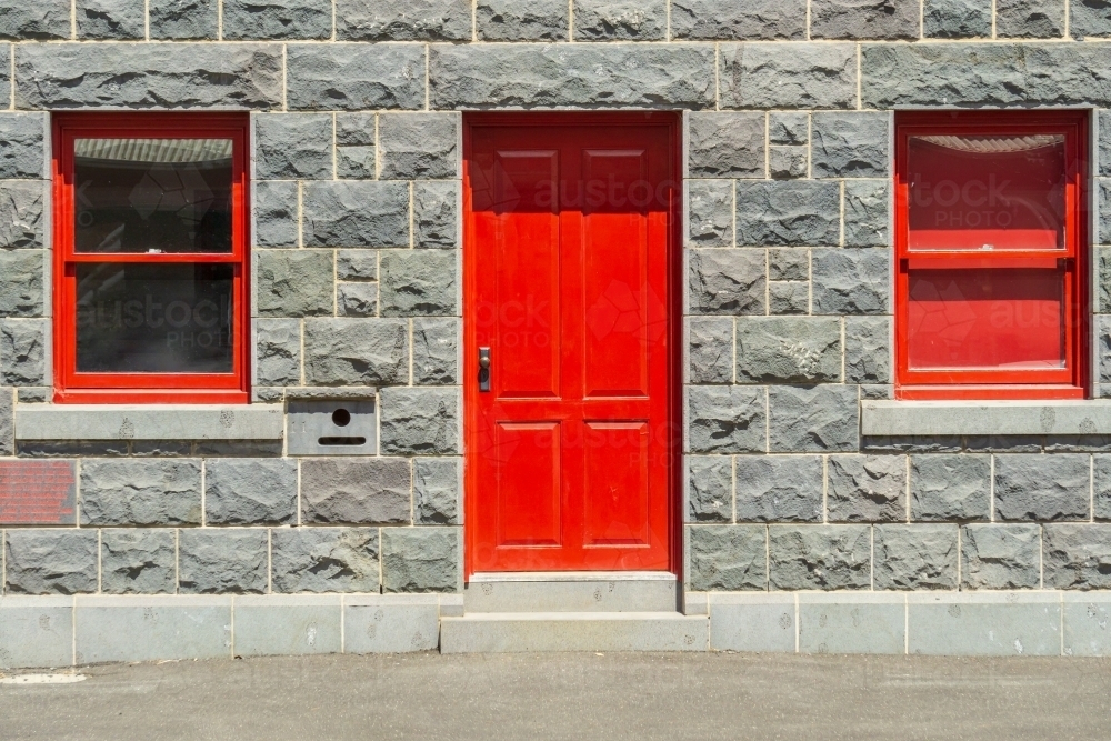 Red windows and doors in the facade of an historic blue stone building - Australian Stock Image