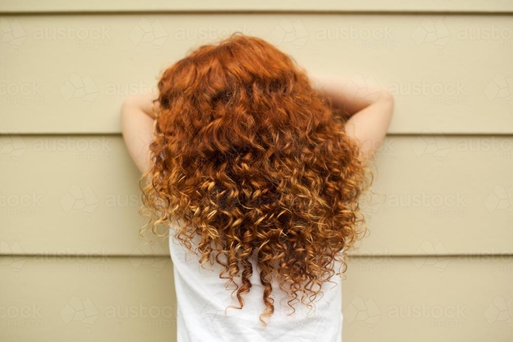 Redhead girl leaning on a wall - Australian Stock Image