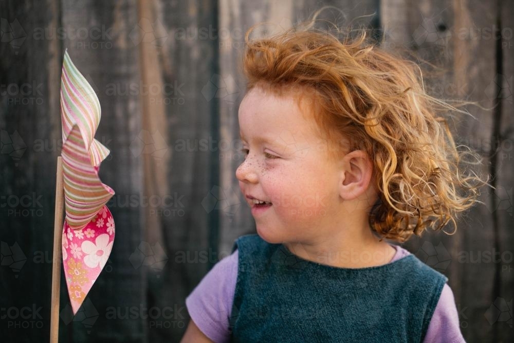 Redhead girl playing with a pinwheel - Australian Stock Image