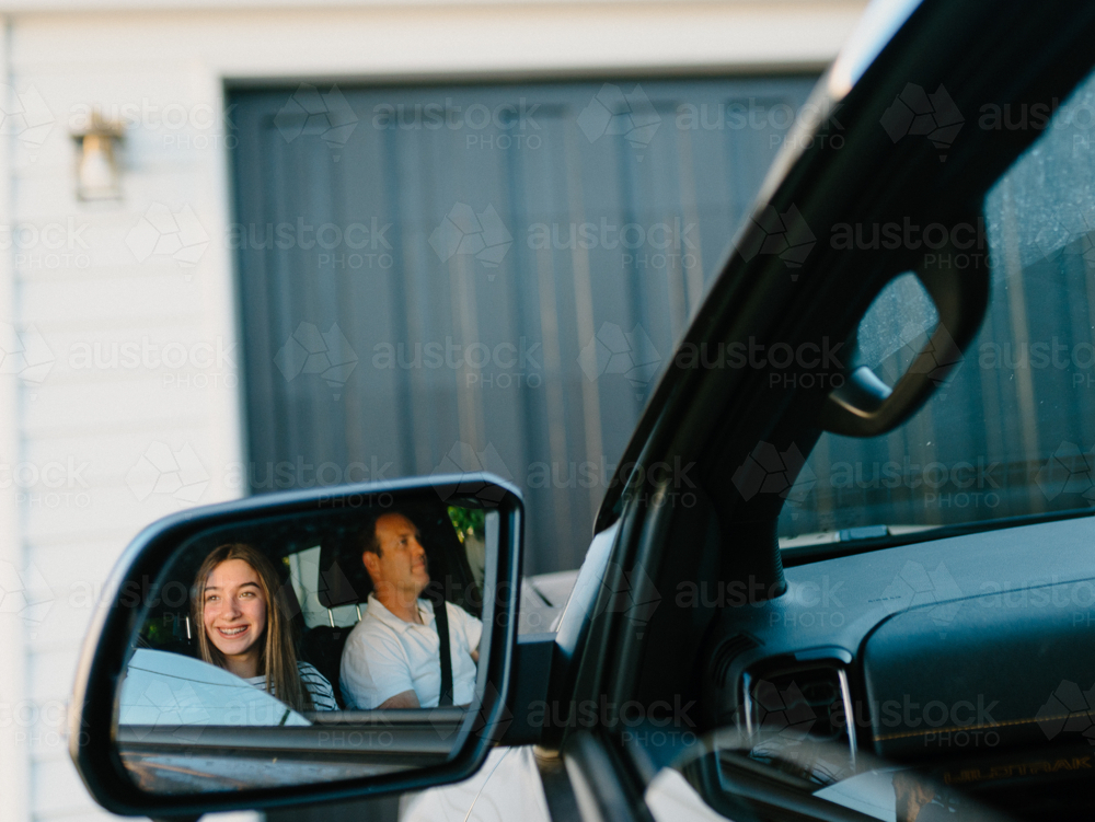 Reflection of a man and young girl inside the car in the rearview mirror. - Australian Stock Image
