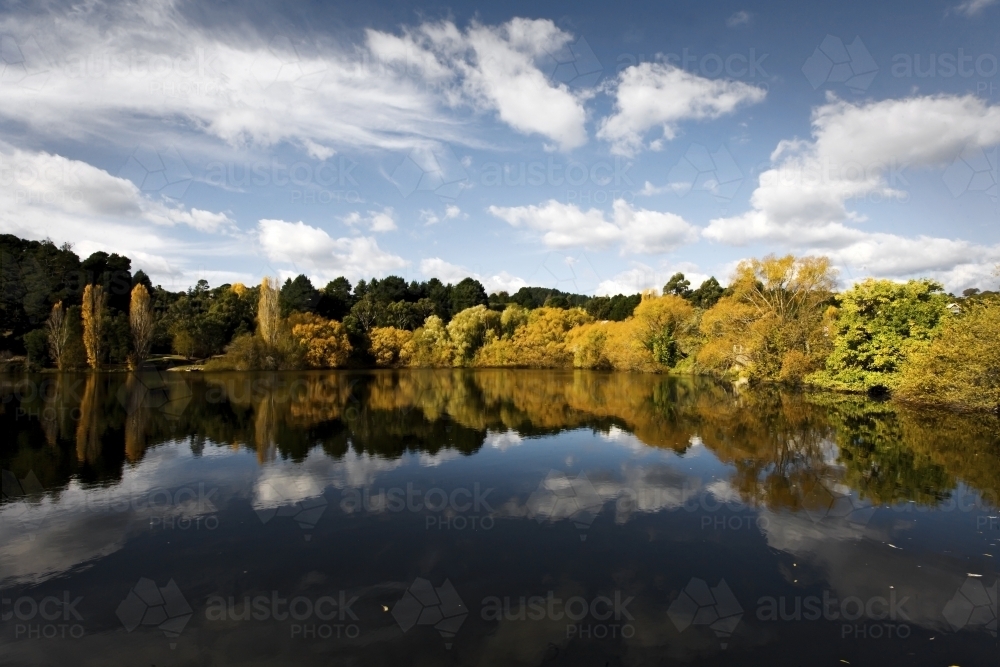 Reflection of clouds and trees in lake - Australian Stock Image
