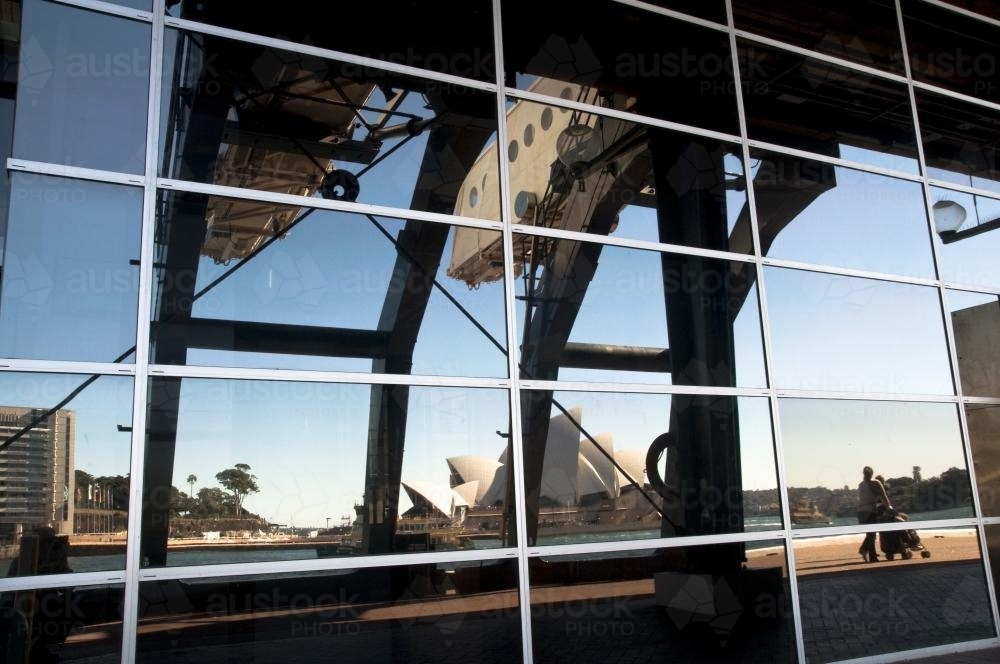 Reflection of passenger loading gantry, Opera House and woman with pram - Australian Stock Image
