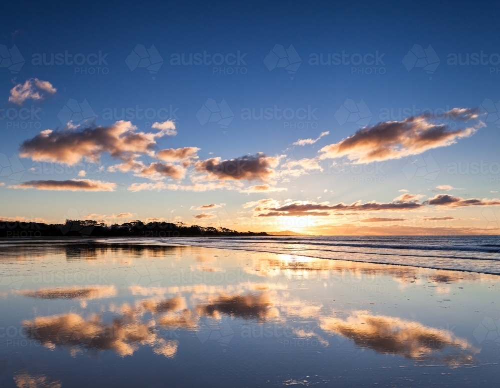 Reflection of sunset sky in wet sand at beach - Australian Stock Image