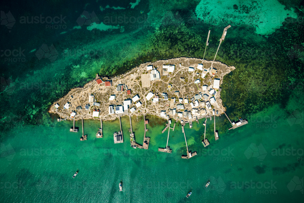 Remote island settlement with rows of shacks and jetties over turquoise water. - Australian Stock Image