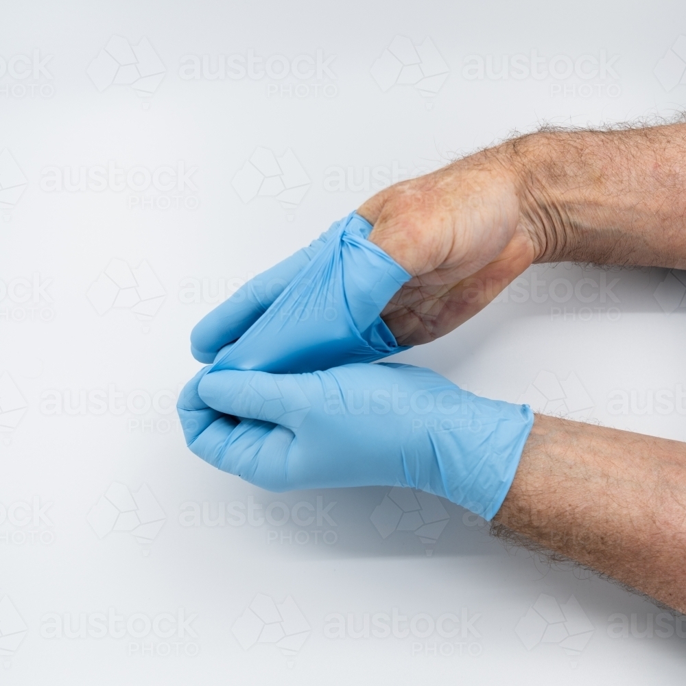 Removing blue medical gloves - Australian Stock Image