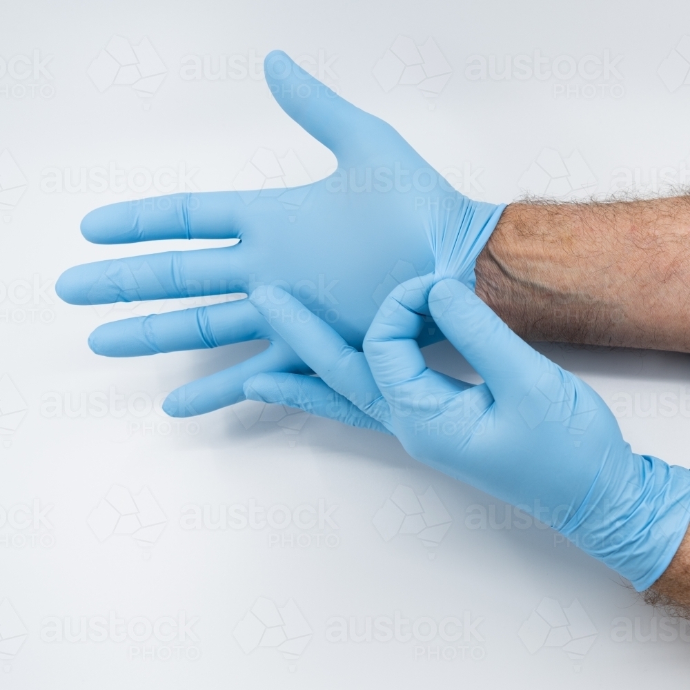 Removing blue medical gloves - Australian Stock Image