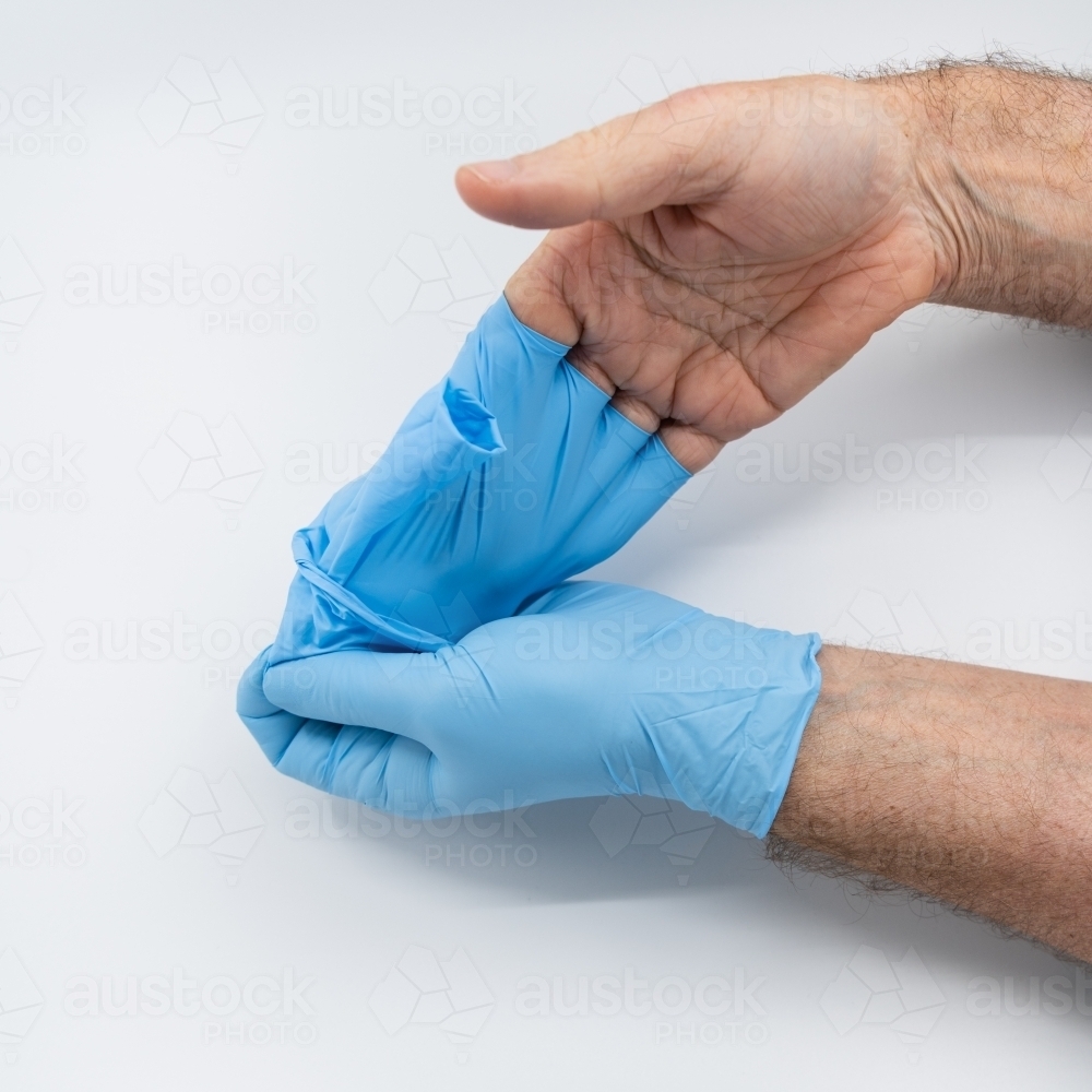 Removing blue medical gloves - Australian Stock Image