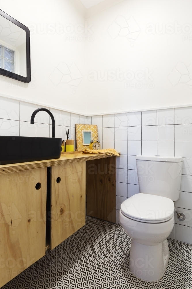 Renovated powder room with decorative floor tiles and black vanity - Australian Stock Image