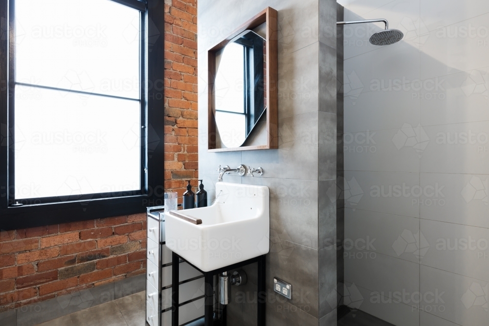 Renovated warehouse bathroom with vintage basin and walk in shower - Australian Stock Image