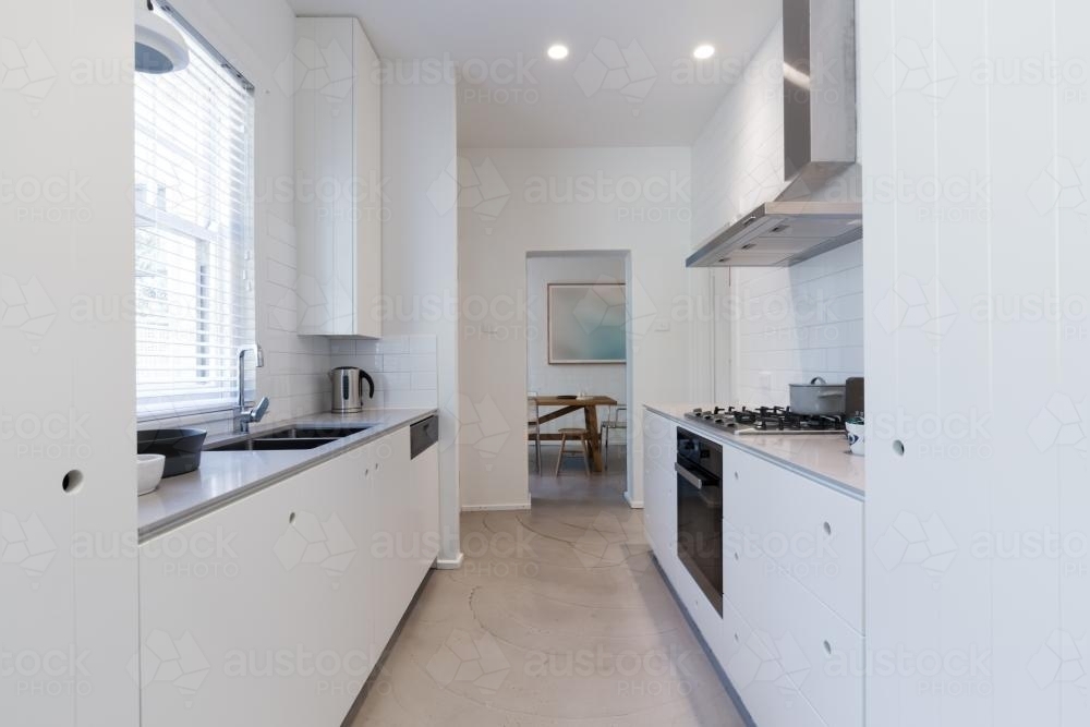 Renovated white galley style kitchen in modern Australian apartment - Australian Stock Image